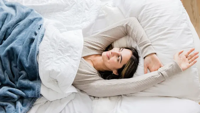 a woman laying on a bed under a blanket