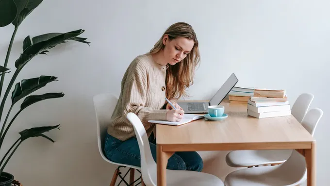 a woman sitting at a table with books and a cup of coffee