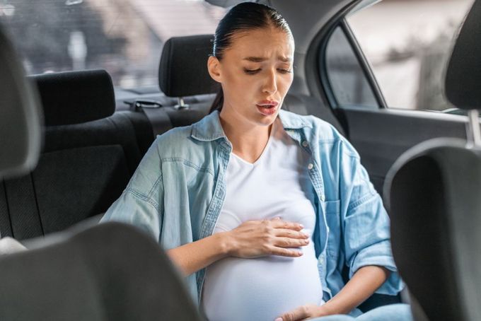 a pregnant woman sitting in the back seat of a car