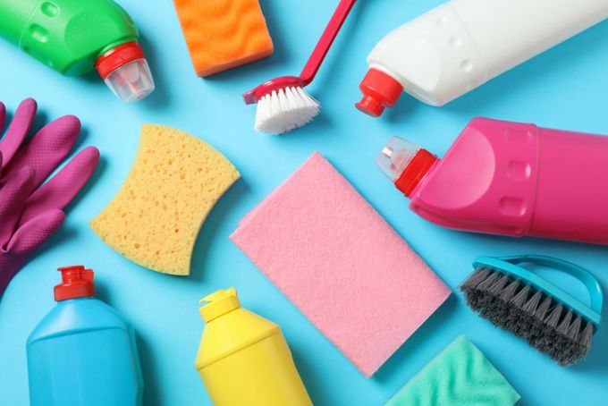 a variety of cleaning supplies laid out on a blue surface