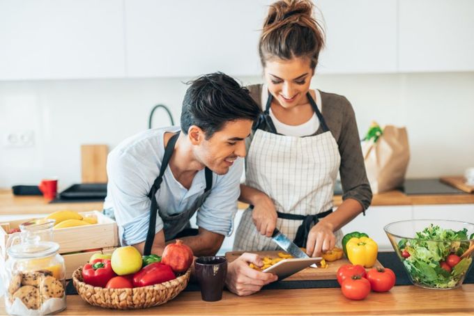 a man and woman preparing food in a kitchen