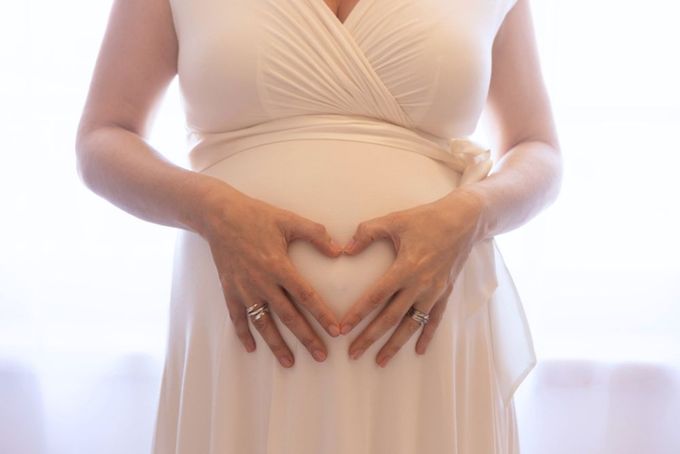 Bump shoot a pregnant woman making a heart shape with her hands