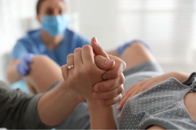 a woman laying on a bed with a man in a medical mask behind her