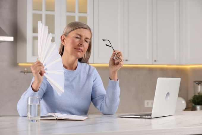 a woman sitting at a kitchen table holding up a pair of scissors