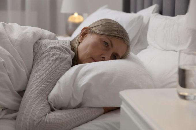a woman laying in bed under a blanket