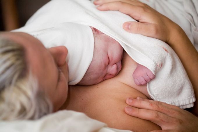 a woman holding a baby wrapped in a blanket