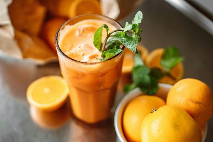 a glass of orange juice next to some oranges