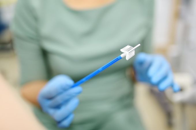 a woman in blue gloves holding a toothbrush
