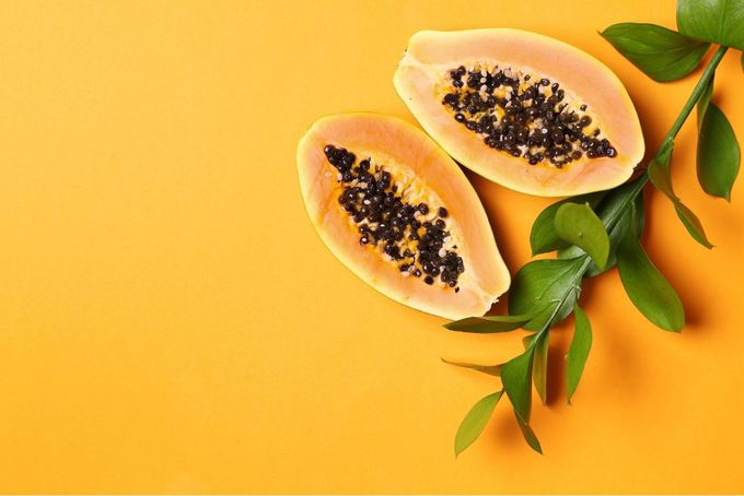 two halves of papaya on a yellow background