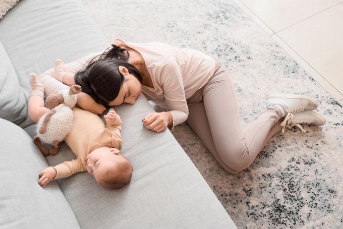 a woman laying on a couch next to a baby