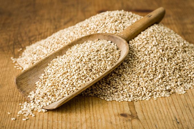 a scoop of sesame seeds next to a pile of sesame seeds