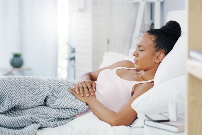 a woman on her period laying in a bed with a blanket