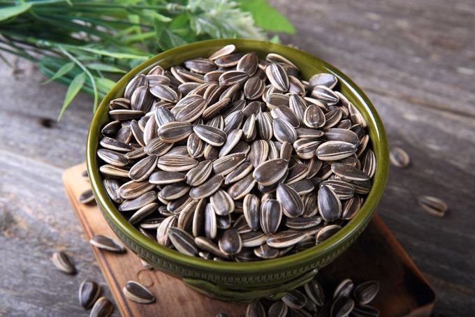 a bowl of sunflower seeds sitting on a cutting board