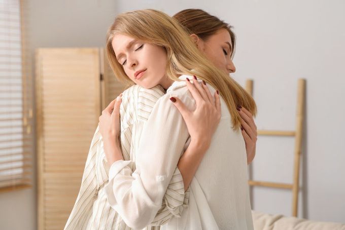 two women hugging each other in a bedroom
