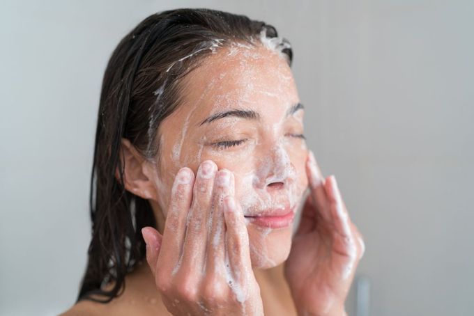 a woman is washing her face with soap
