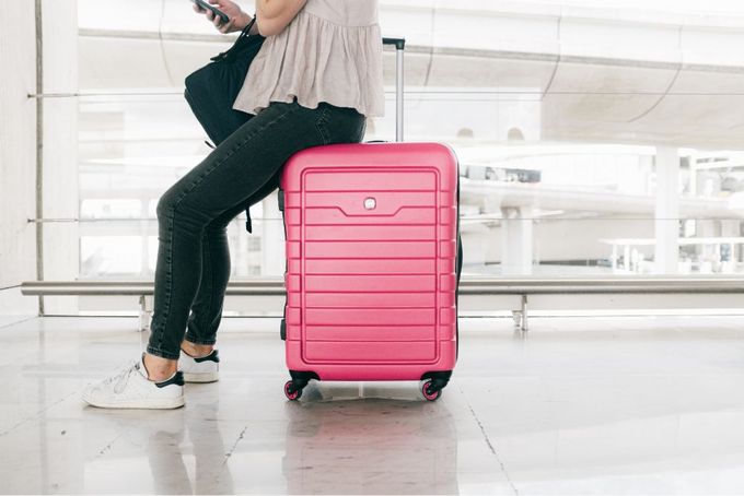 a woman sitting on top of a pink suitcase