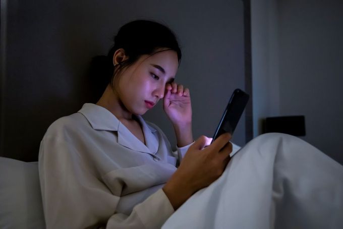 a woman sitting on a bed looking at a cell phone