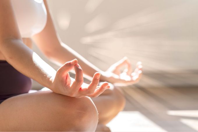 a woman sitting in a lotus position with her hands in the air