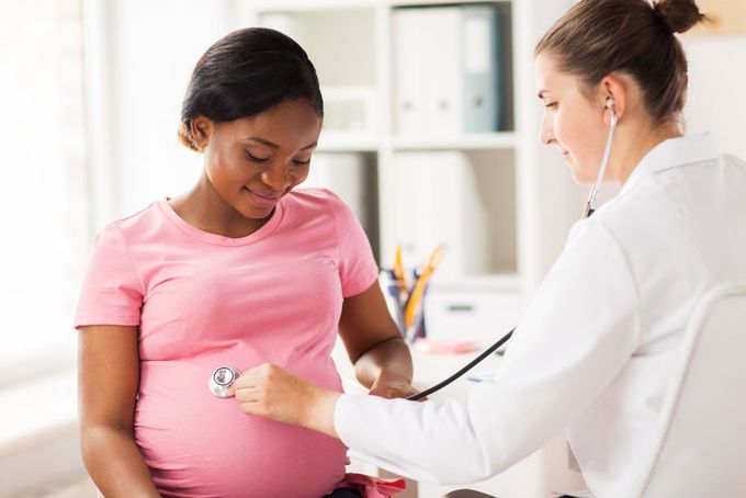 a pregnant woman is listening to a doctor's stethoscope