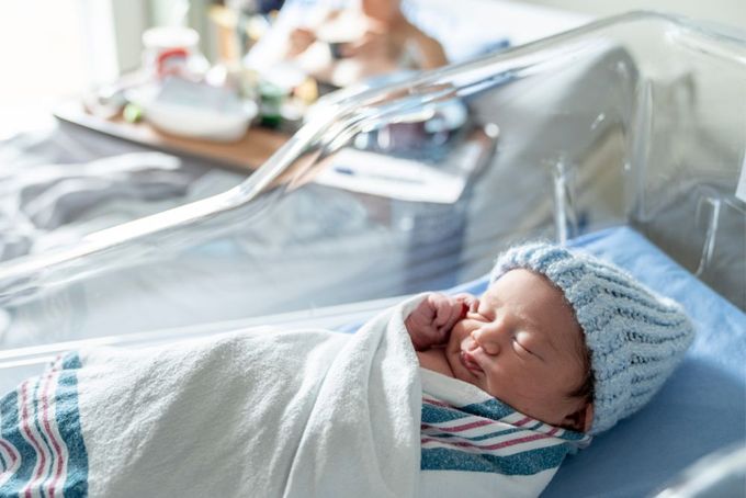 a baby wrapped in a blanket in a hospital bed