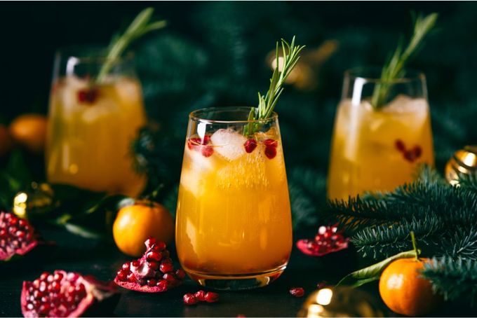two glasses of orange punch with rosemary garnish