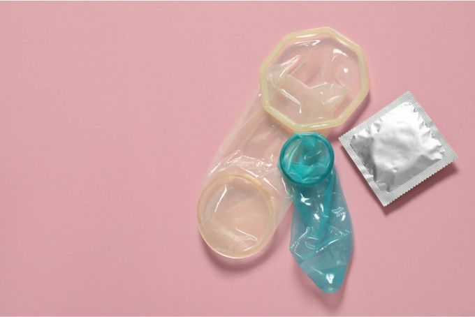 a condom and a condom bag on a pink surface