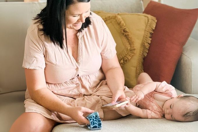 a woman sitting on a couch playing with a baby