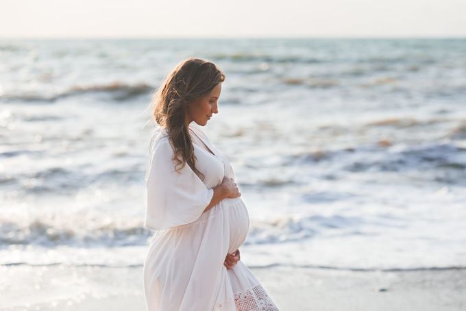 a pregnant woman walking along the beach