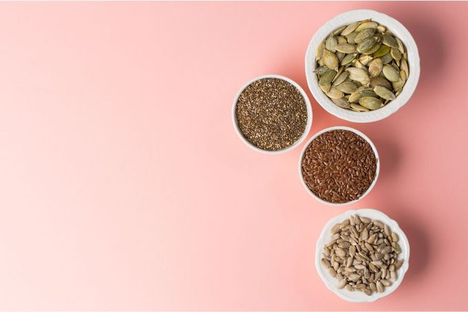 three bowls filled with seeds on a pink background