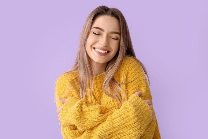 a smiling woman in a yellow sweater