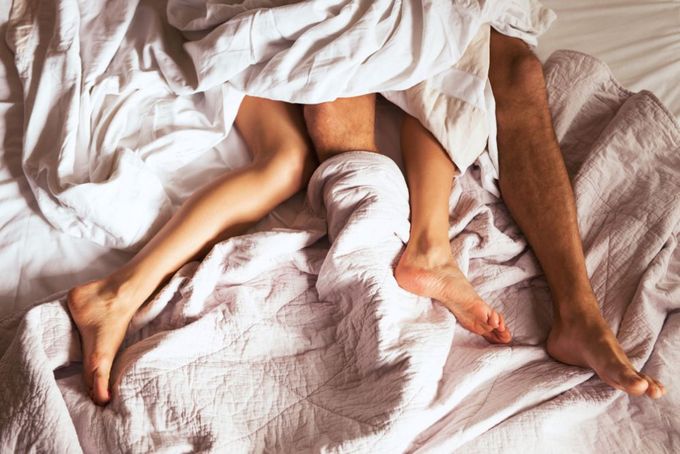 a man and woman laying in bed under a blanket