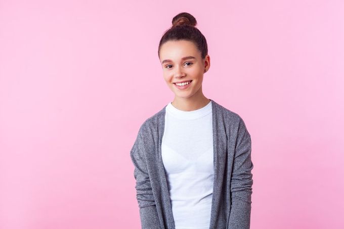 a woman standing in front of a pink background