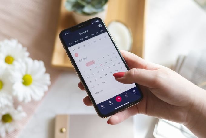 a person holding a cell phone with a calendar on the screen