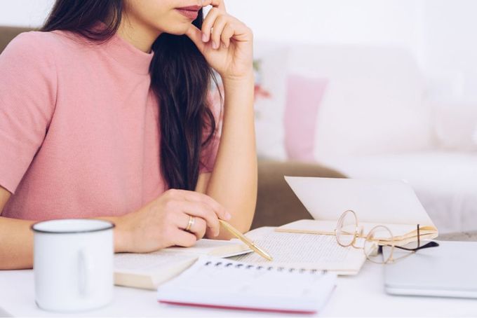 a woman sitting at a table with a notebook and pen