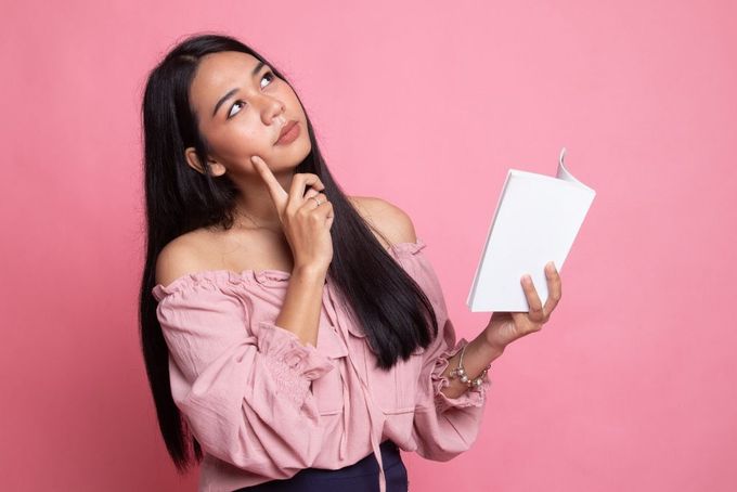 a woman in a pink shirt is holding a book