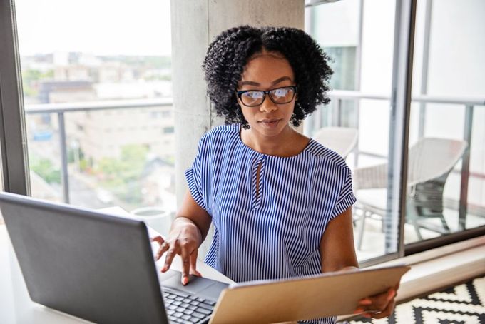 a woman in glasses is looking at a laptop
