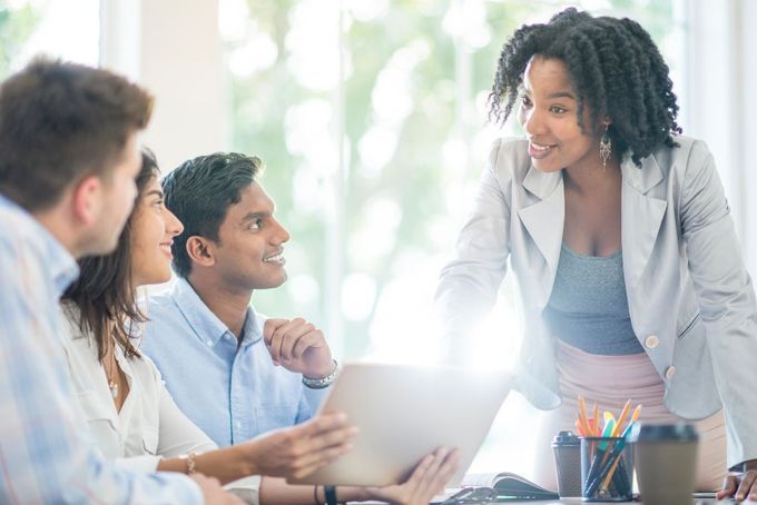 a group of people sitting around a table with a laptop