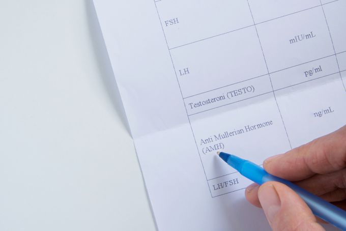 A person writing on a piece of paper with a blue pen.