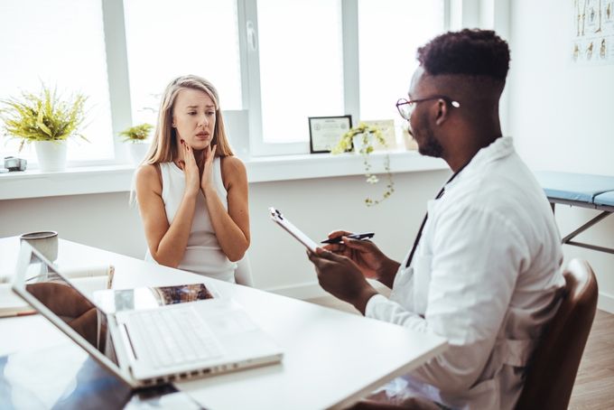 A woman learning about thyroid issues from a doctor.