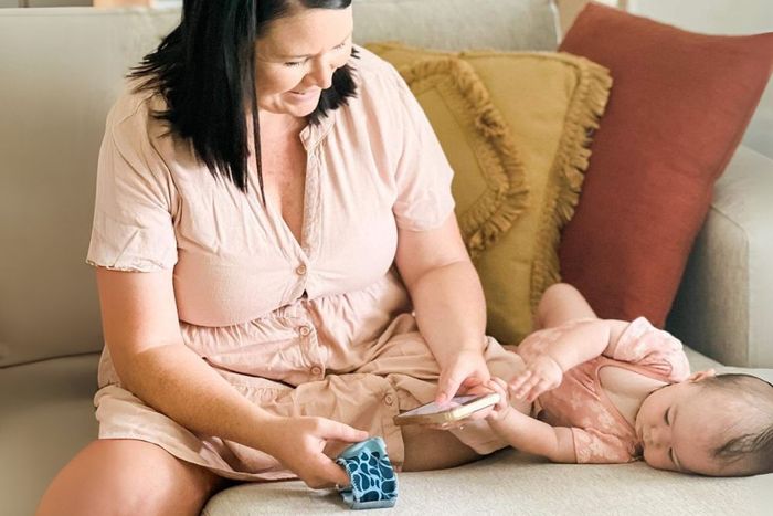 a woman sitting on a couch playing with a baby