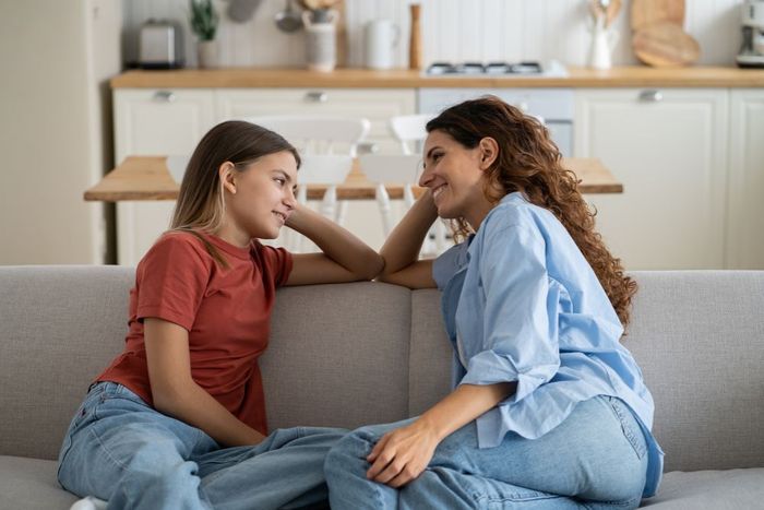 two women sitting on a couch talking to each other
