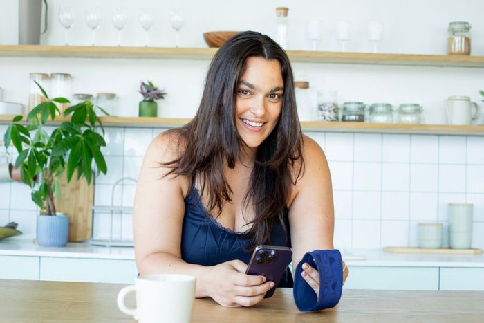 a woman sitting at a table holding a cell phone