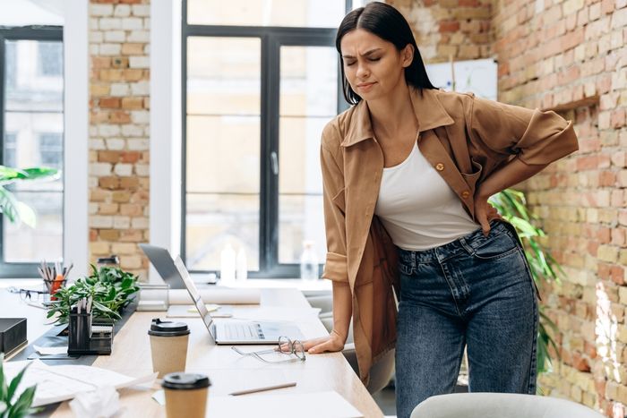 a woman in work office experiencing period pain and period cramps