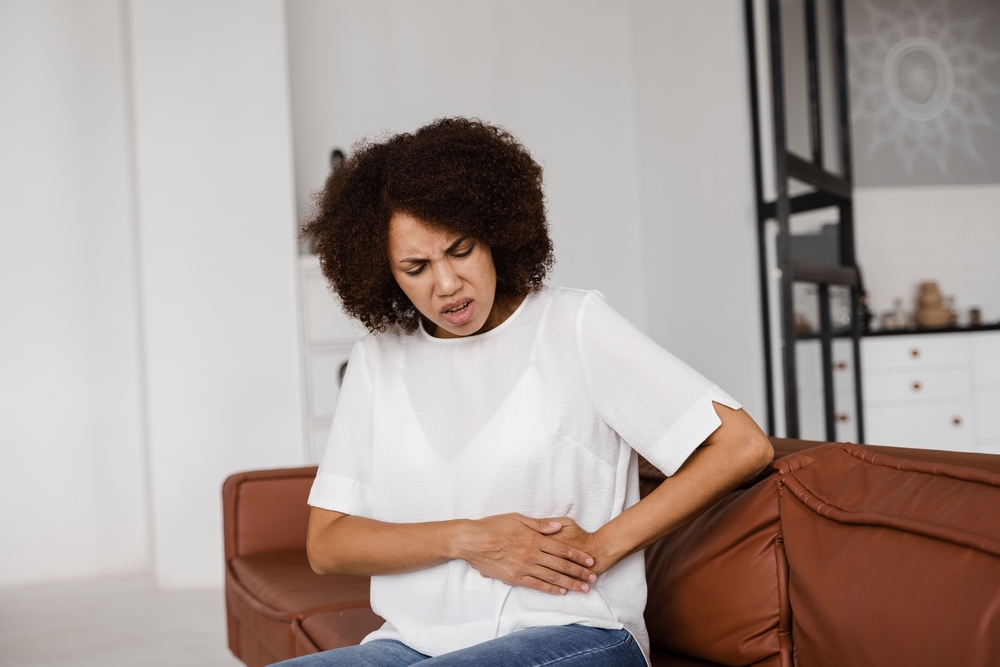 A woman holding her stomach due to chronic pain.