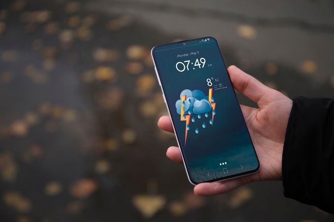 A person holding a cell phone in their hand reading weather data