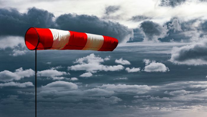 A red and white-striped wind sock blowing east due to wind gusts
