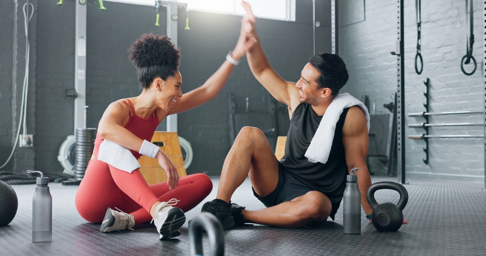 Two people high-fiving after a workout in the gym, keeping their metabolism high