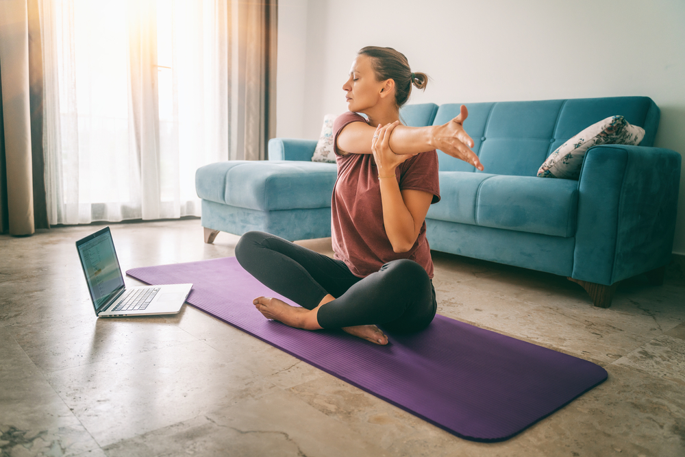 A woman gently exercising at home, symbolizing low-impact workouts one can do while feeling unwell
