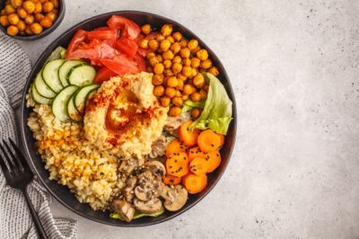 Vegetables, chickpeas, hummus, mushrooms, and spices in a bowl
