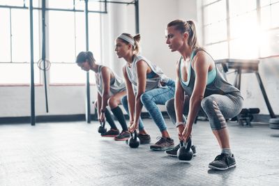 Three women doing kettlebell exercises in the gym